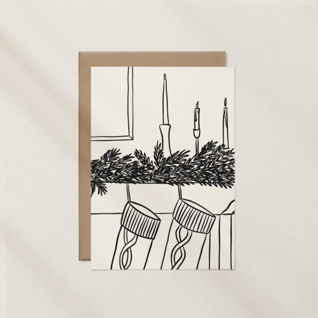 A black and white drawn card of stockings hanging on the fire place