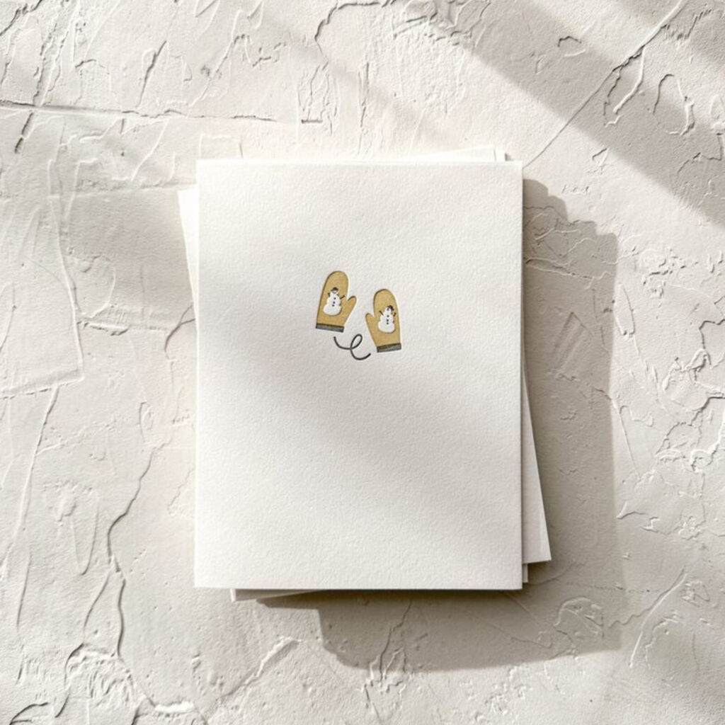 A white card with two gloves which both have snowmen on
