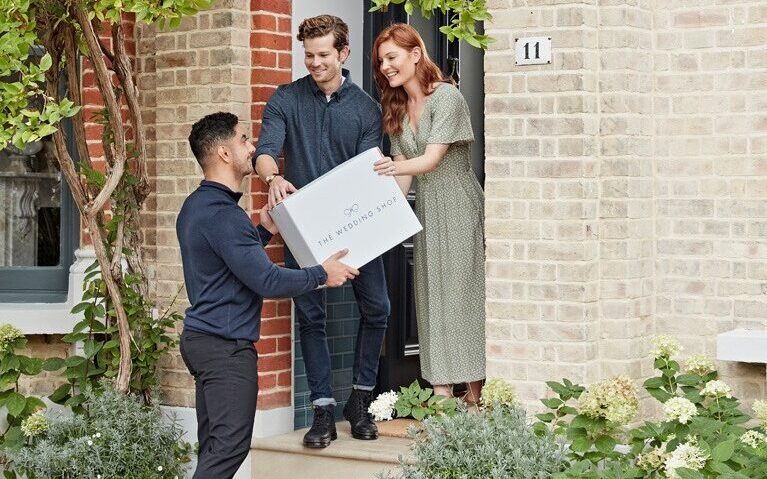 A couple getting a parcel delivered from the wedding shop