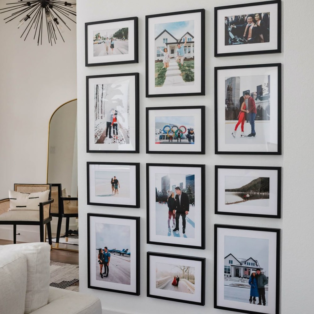 A gallery wall of photographs, all in black frames on a white wall.
