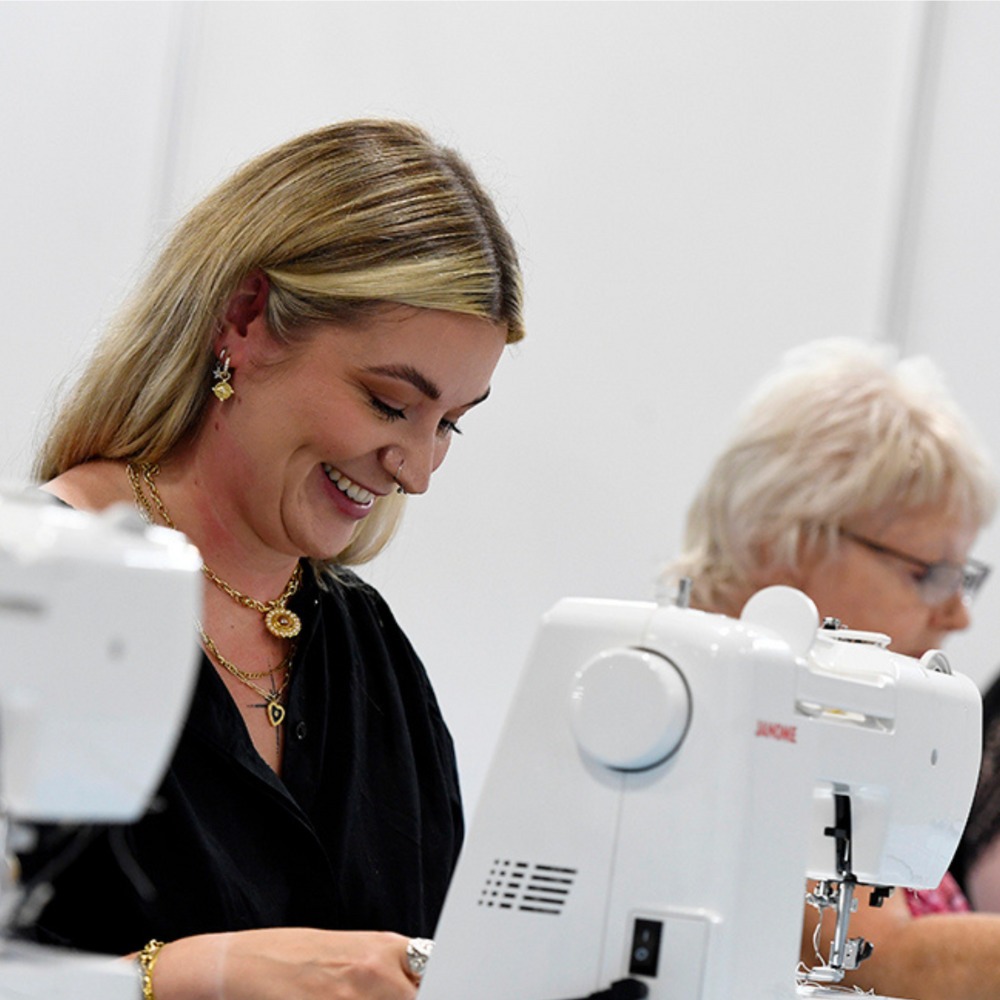 A woman smiling as she takes part in a sewing workshop.