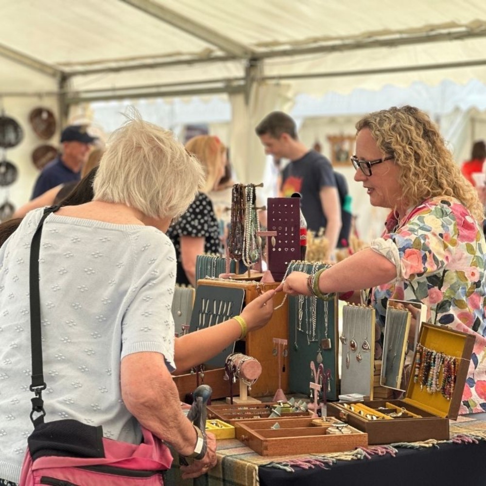 A jewellery stall holder chatting to visitors.