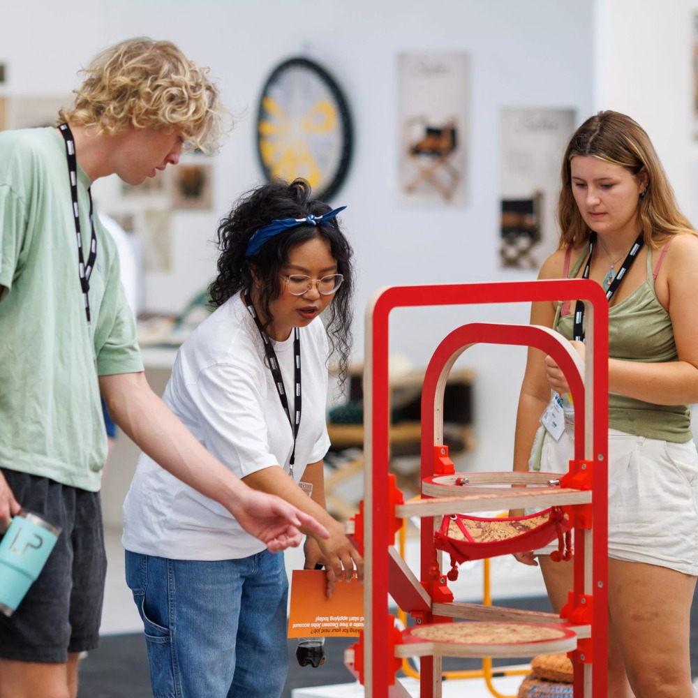 Three graduates in discussion at the New Designers trade show.