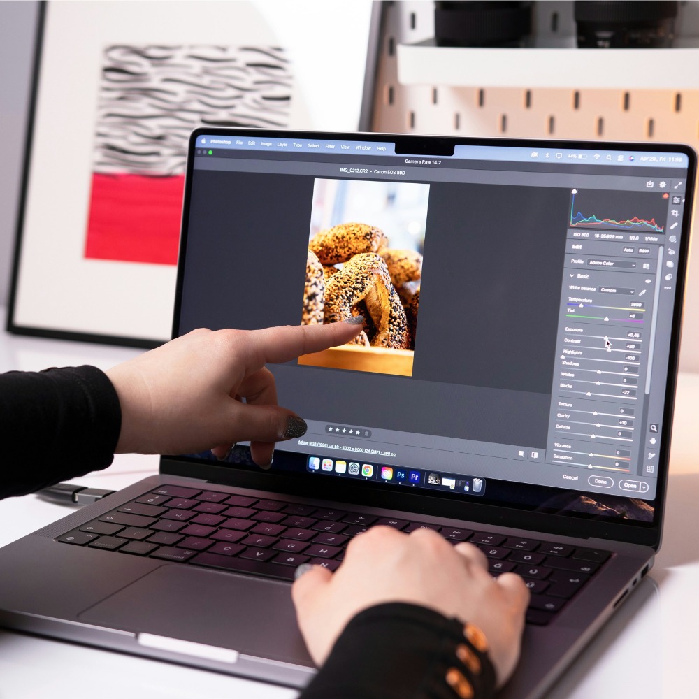 Someone editing an image on a laptop. They are pointing at it with their left hand.
