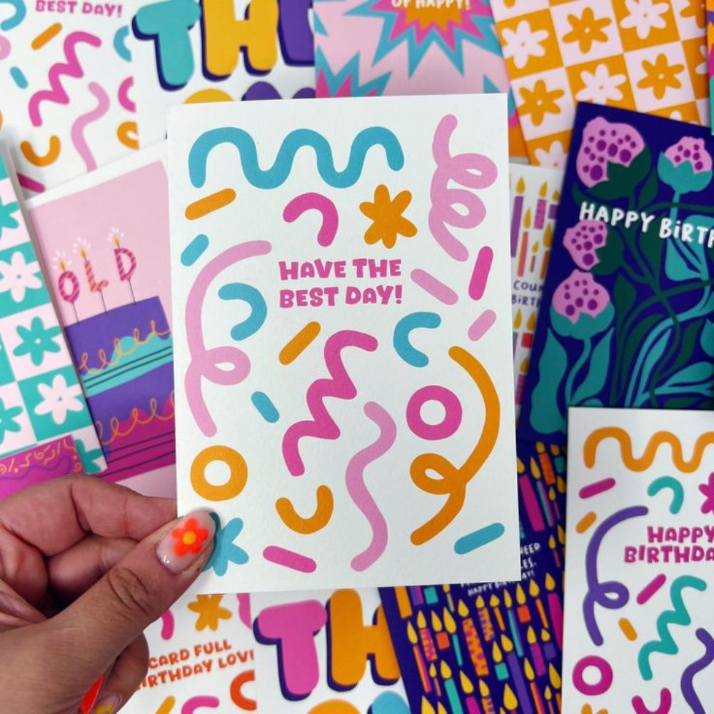 Bright card covered in playful colourful squiggles and shapes with the message “Have the best day!”