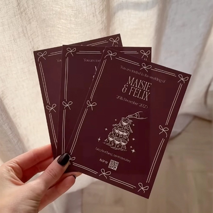 Burgundy wedding invitations with white text and illustrations.