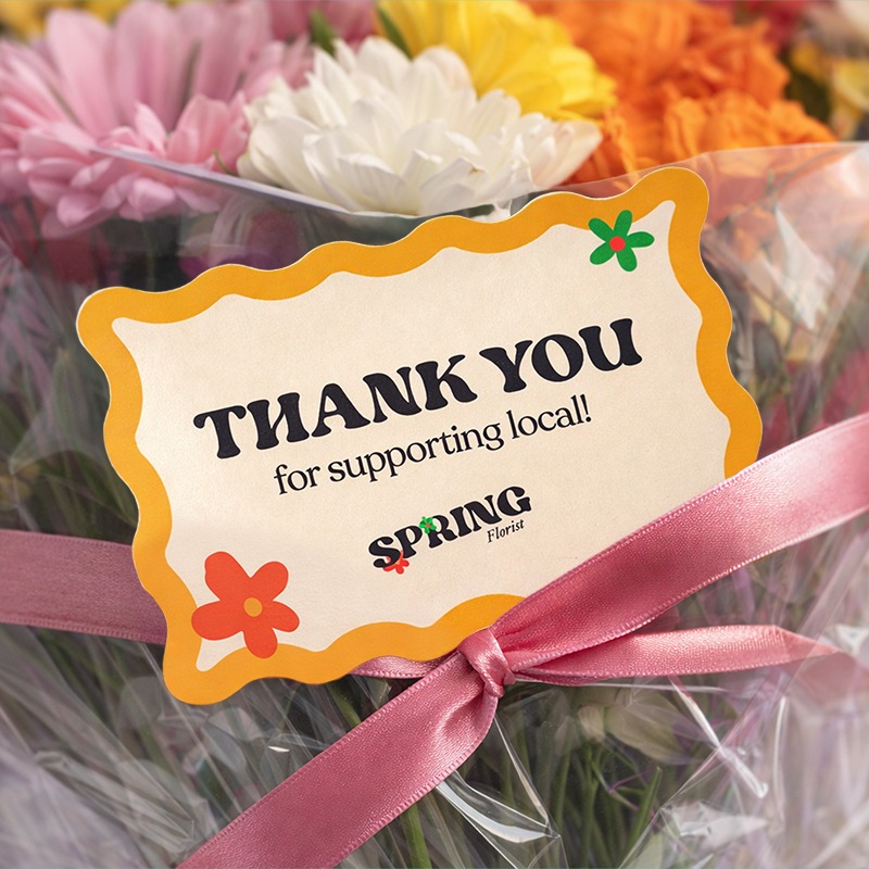 A wave cut thank you card attached to a bunch of flowers. 