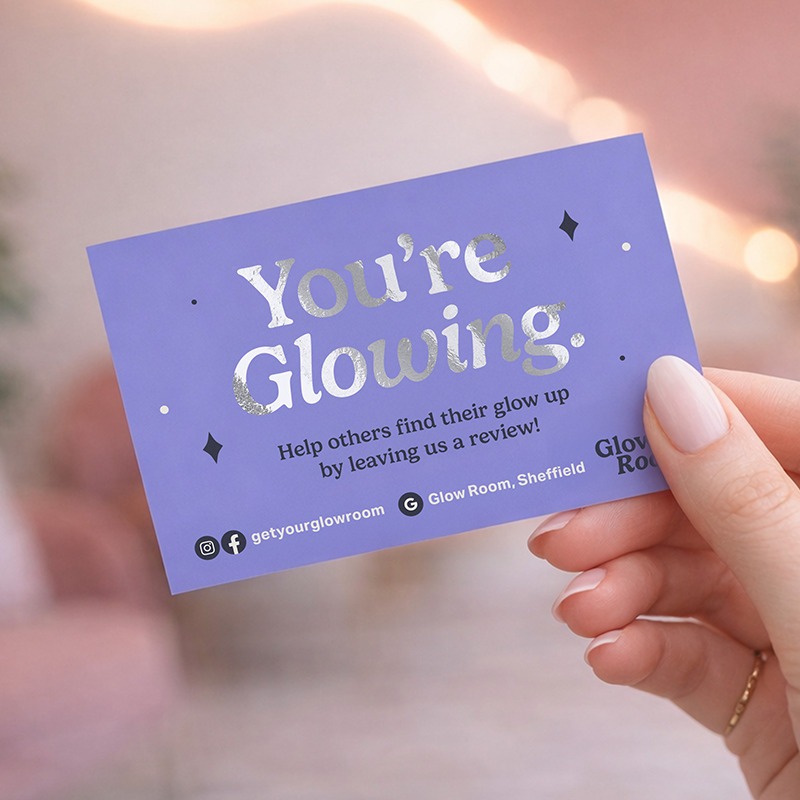 A hand holding a purple card with text that asks customers to leave a review.