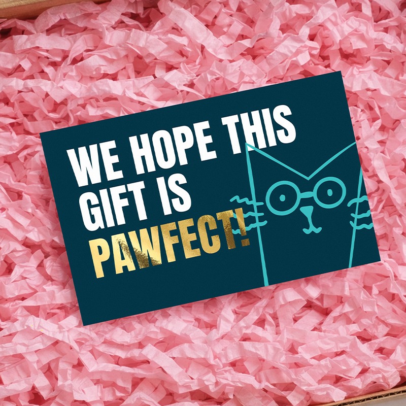 A card placed in packaging with pink shredded paper, with a heart warming message.