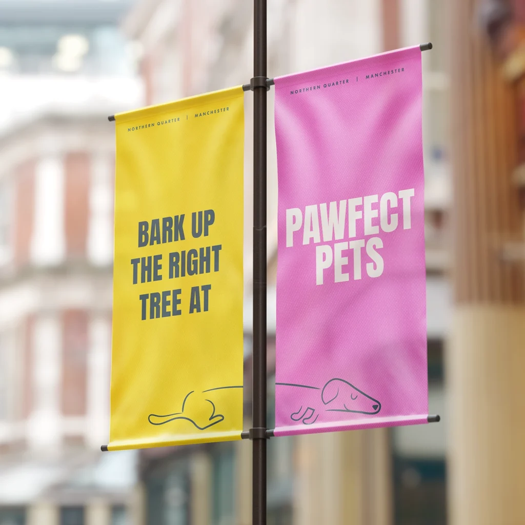 Two Branded Flags, the one on the left is yellow, the one on the right is pink. Together they read "bark up the right tree at Pawfect Pets".