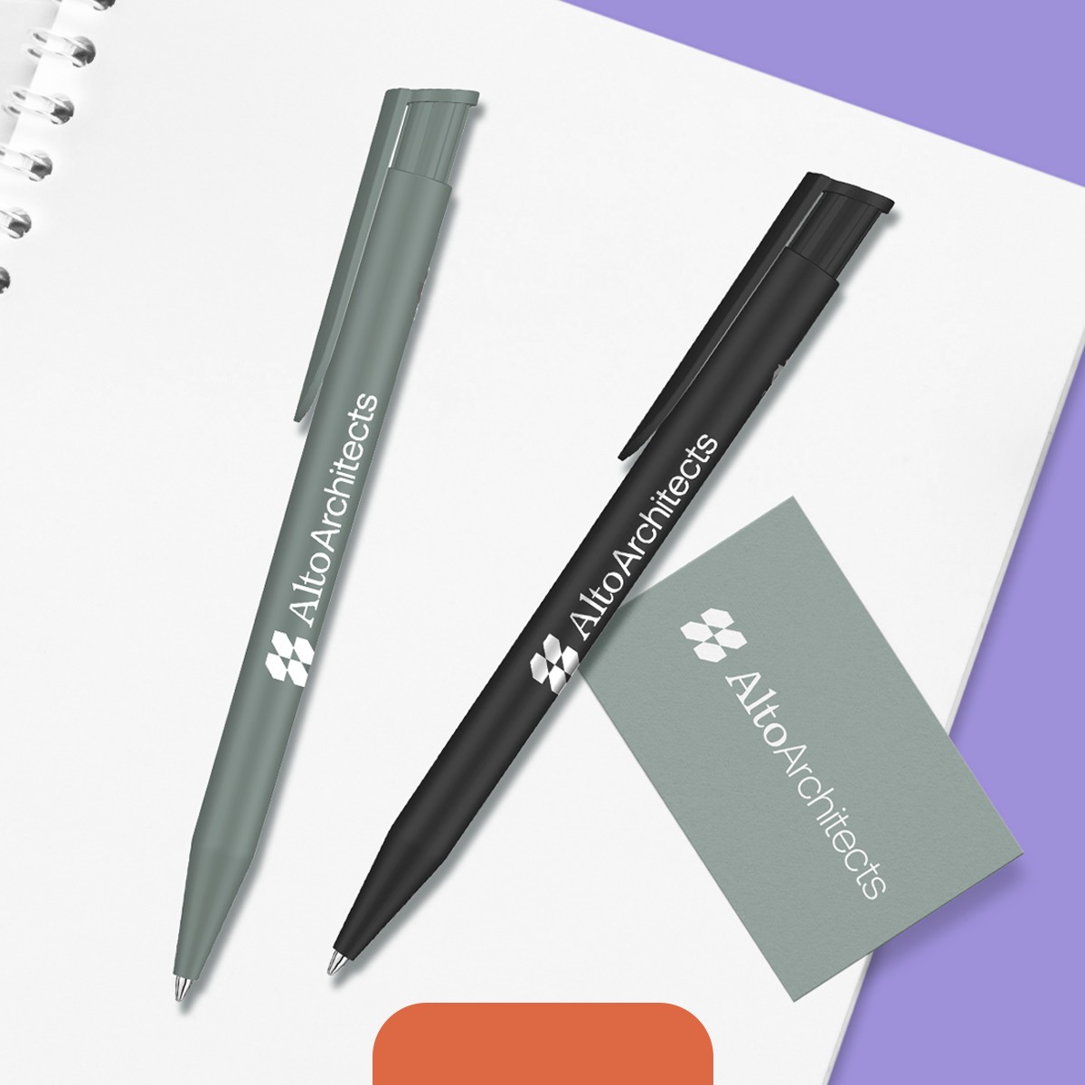 Two Branded Pens and a Business Card photographed against a white notebook.