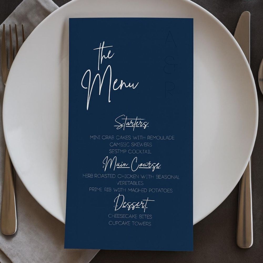 A dark navy coloured Wedding Menu on top of a plate. 