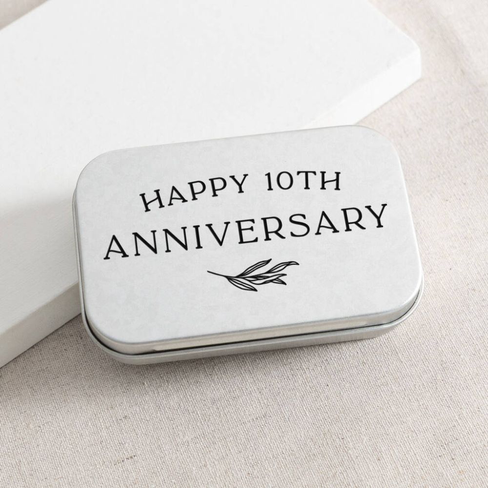 A small silver tin with black text on it saying "happy 10th anniversary"