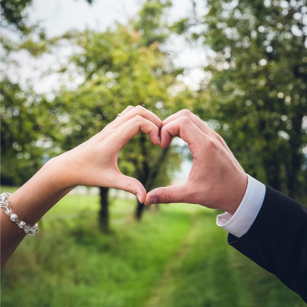 Two hands joining together to make a heart shape.