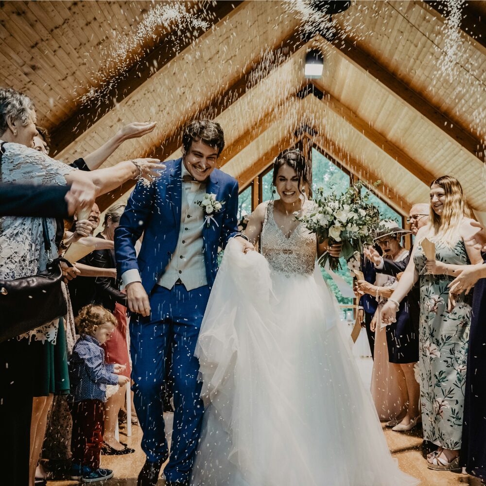 A just-married couple walking back down the aisle as confetti is thrown.