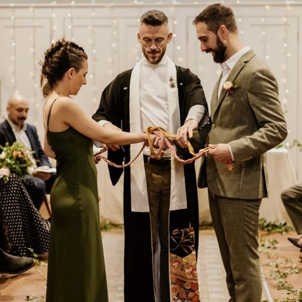 A couple engaged in a hand fasting ritual at their wedding.
