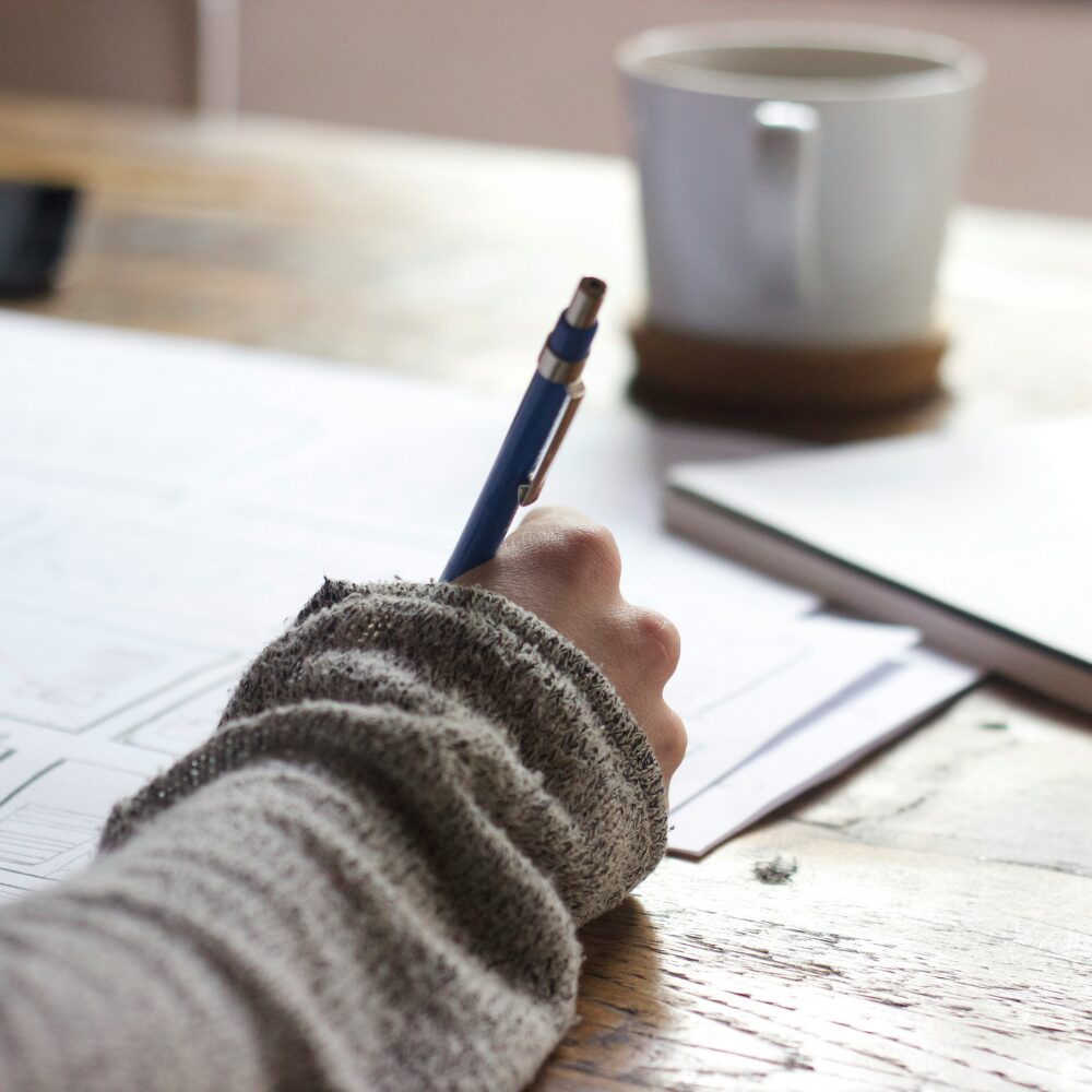 A close-up image of a hand holding a pen, writing. 