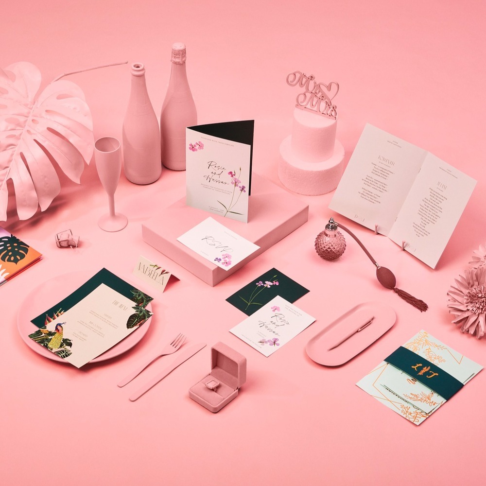 A selection of Wedding Stationery on a pink background. 