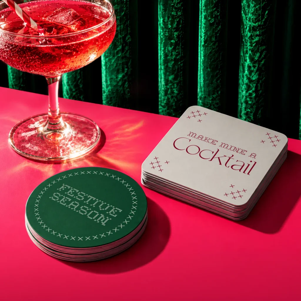 Two piles of printed Christmas Coasters - one says 'make me a cocktail' the other says 'festive season'. 