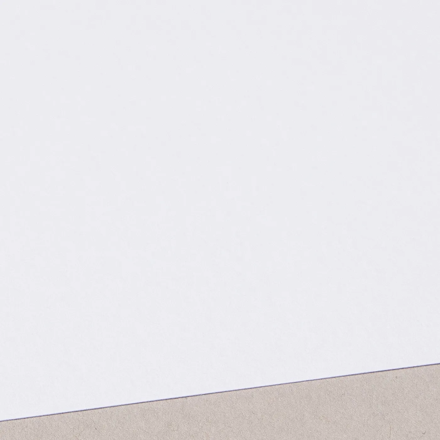 Close-up of an uncoated textured white sheet of paper on a flat surface.