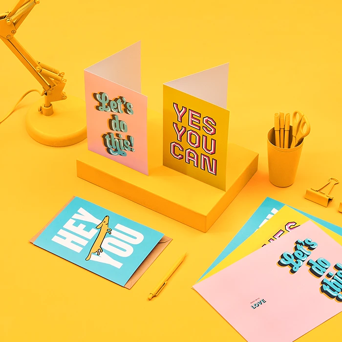 Folded greeting cards in various colors and patterns displayed on a yellow background
