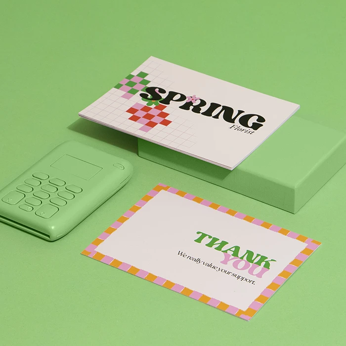 Assorted postcards with vibrant designs laid out on a light green surface