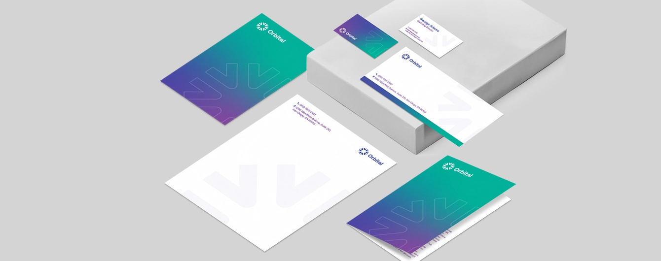 A variety of business stationery including letterheads, compliment slips and business cards with matching colorful white, green and purple minimalist design on a plain background.