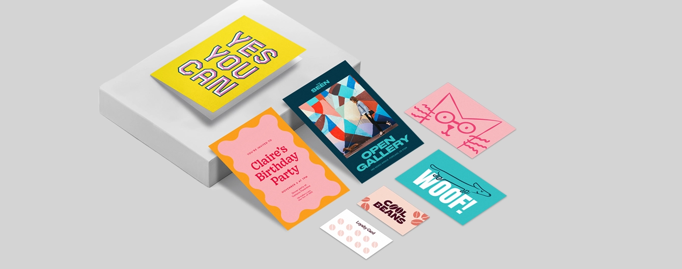 Various greeting cards, invitations, postcards and loyalty cards with bold colorful designs on a plain background.