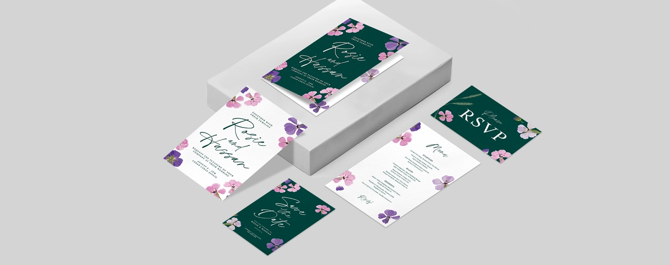 Various wedding print including invitations, save the dates and rsvp cards featuring a simple white, green, pink and purple floral design on a plain background.
