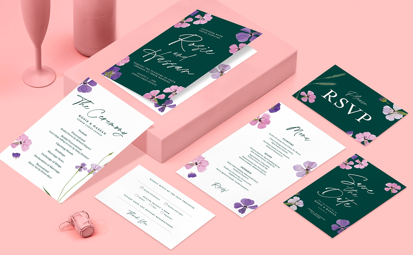 A selection of wedding print products including invitations, RSVP cards and save the date cards featuring a floral design, on a soft pink background with a champagne bottle, flute and cork.