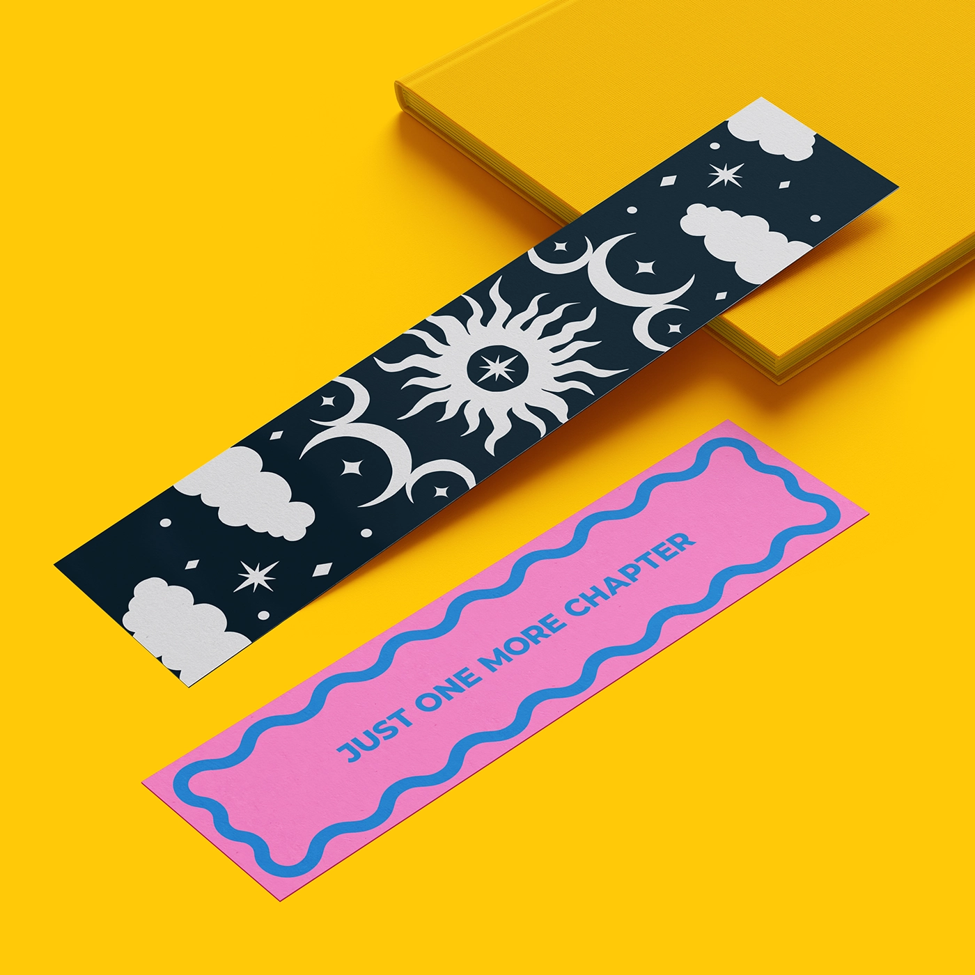 Two bookmarks, one with a pink design reading 'just one more chapter' and one with a black and white design featuring stars, moons and clouds on a bright yellow background.