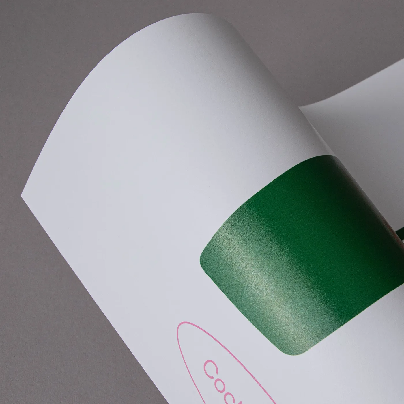 Curved white paper printed with a green area showing the shine of the paper, on a grey background.