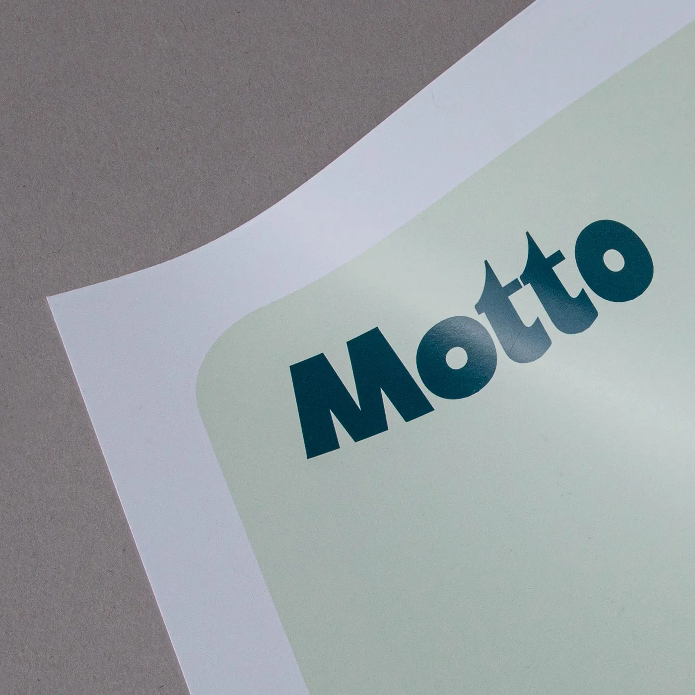Corner of a white sheet of paper printed with a green design and the text 'Motto'.