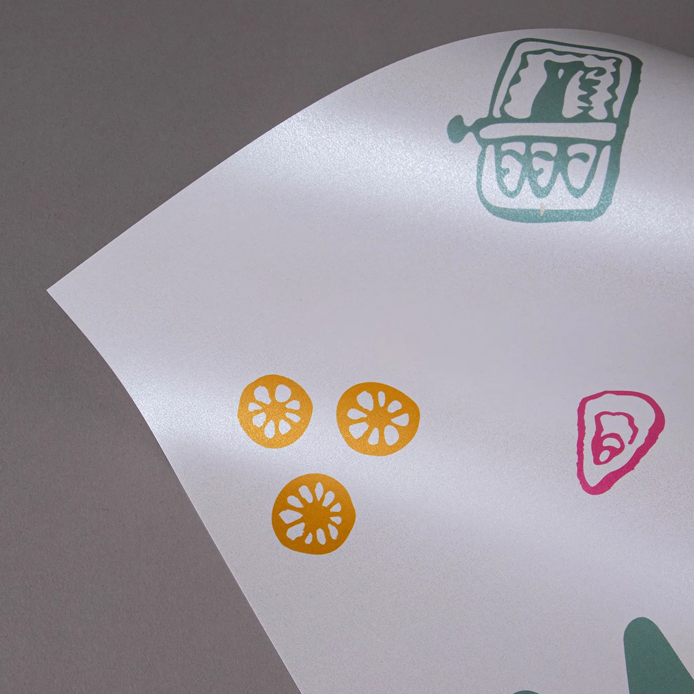 Close up image of Pearlescent paper printed with green, yellow and pink elements, and positioned in a curve demonstrating the shine.