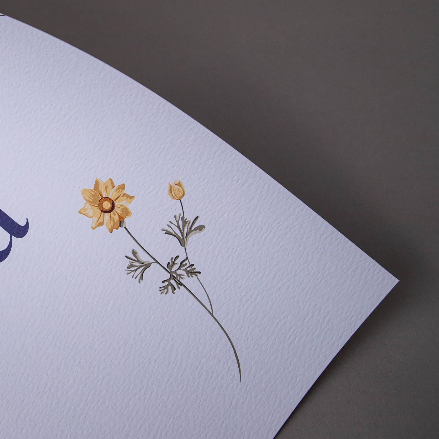 Close up of the corner of a white sheet of paper with a hammered texture and a small yellow floral design.