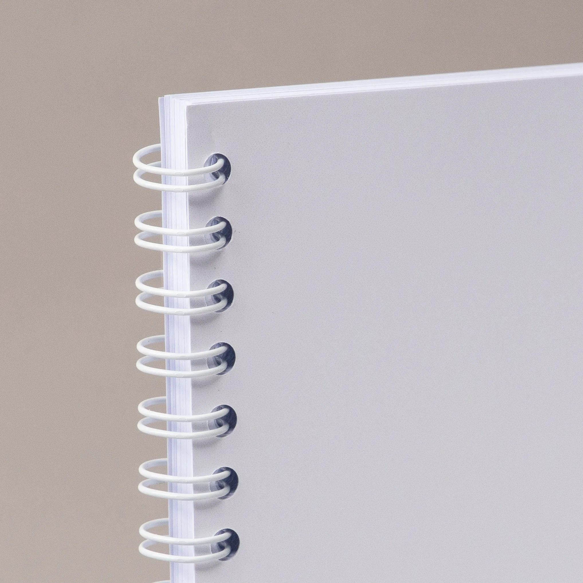 White spiral binding on the left edge of blank paper, shown on a plain gray background.