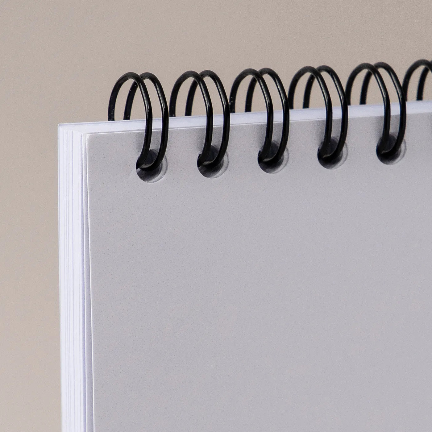 Black spiral wire binding shown in a plain paper book on a plain gray background.