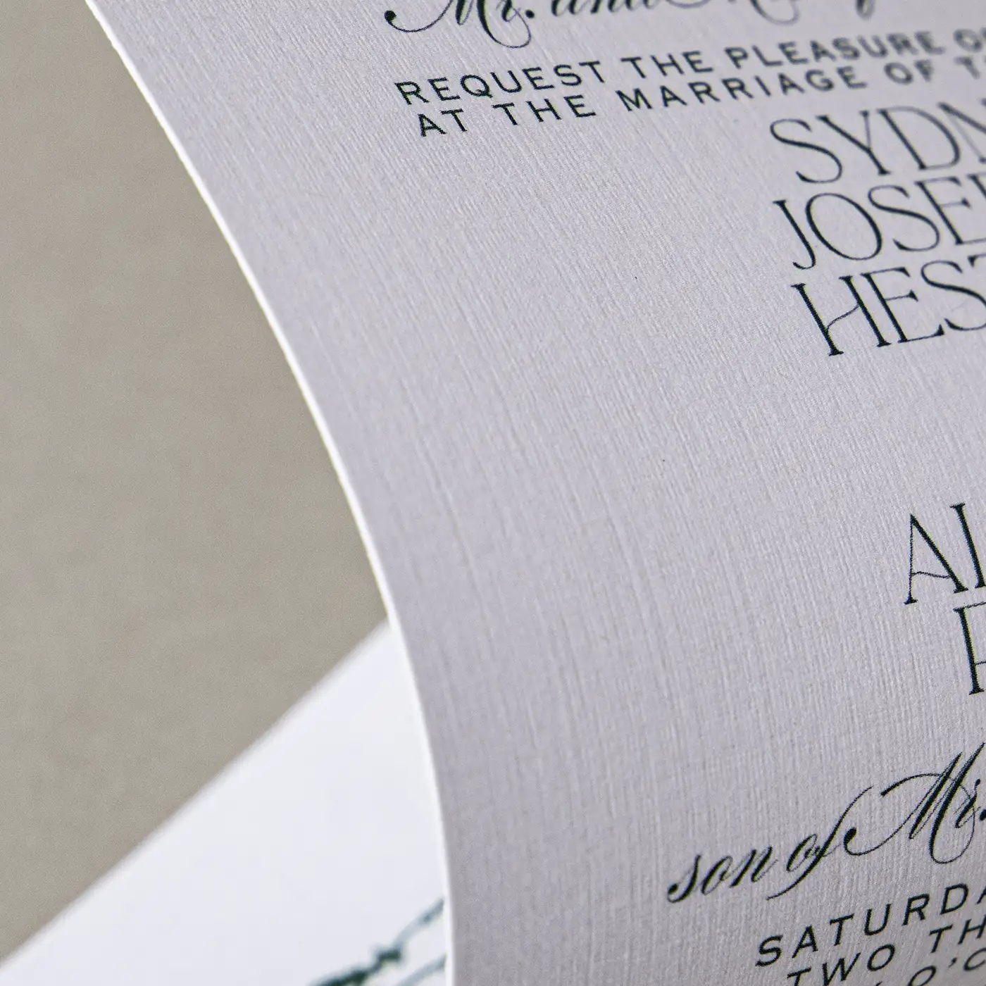 Close up image of curved white linen paper with printed dark green text.