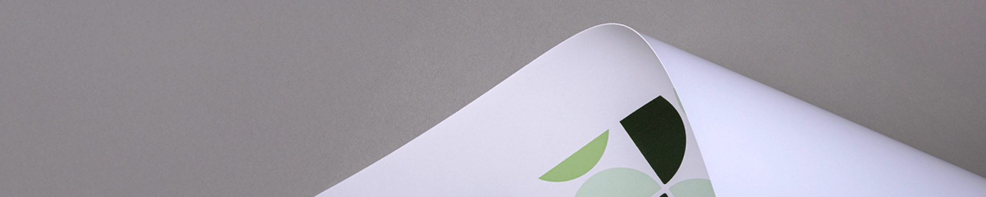 Printed.com Papers Curved paper close-up with green print, on a grey background.
