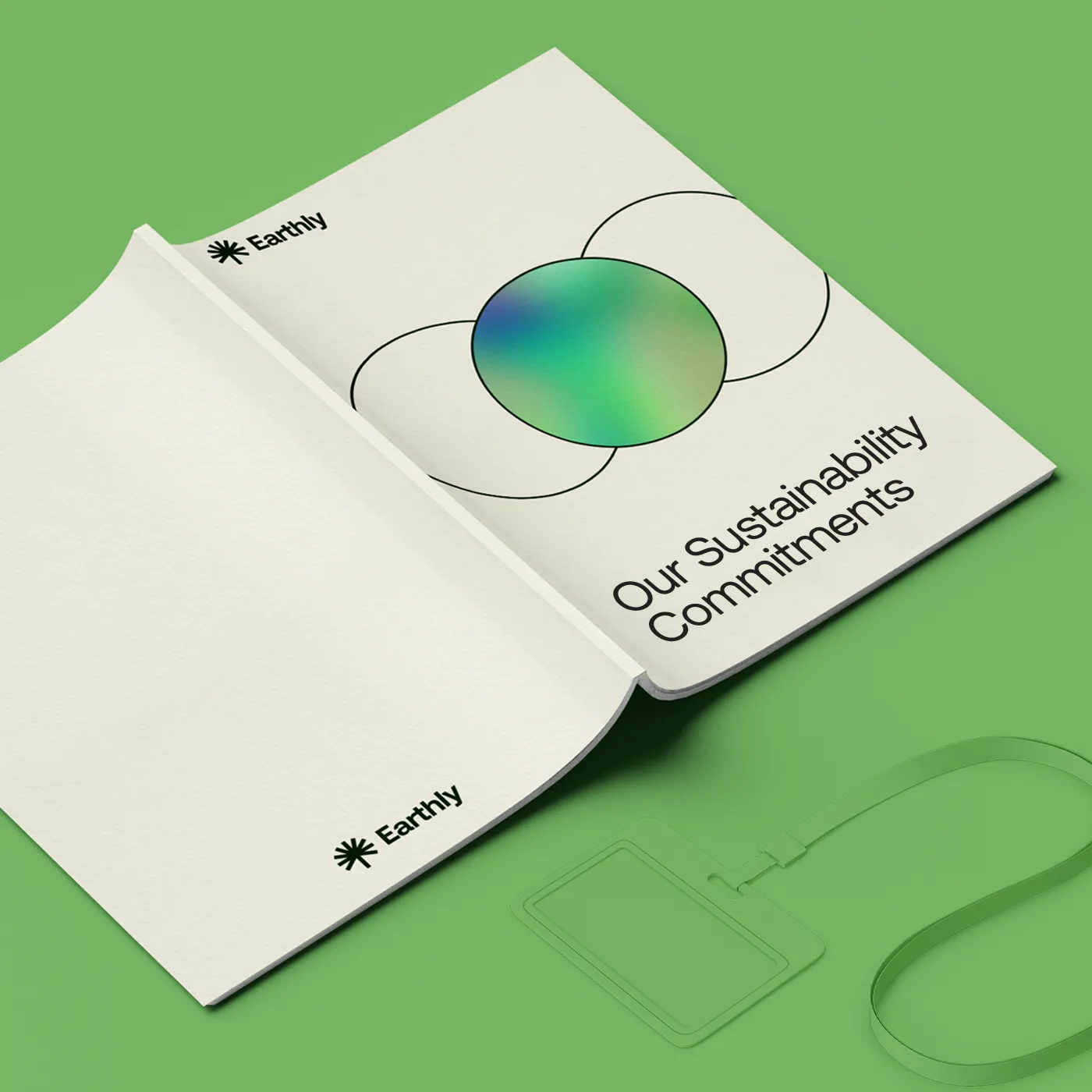 An open, perfect-bound booklet titled "Our Sustainability Commitments" by Earthly is displayed on a green surface. The cover features a minimalist design with a vibrant green and blue gradient sphere within overlapping circles, accompanied by a matching green lanyard and ID badge holder.
