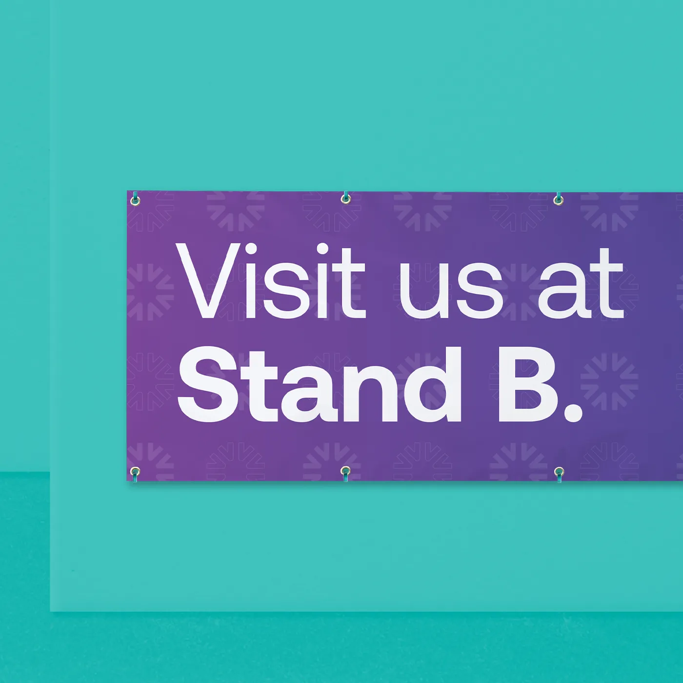 A purple promotional vinyl banner is mounted on a bright teal wall. The banner contains the white text "Visit us at Stand B." over a faint pattern of repeating brand icons. The banner is secured with metal grommets at the corners and along the edges.