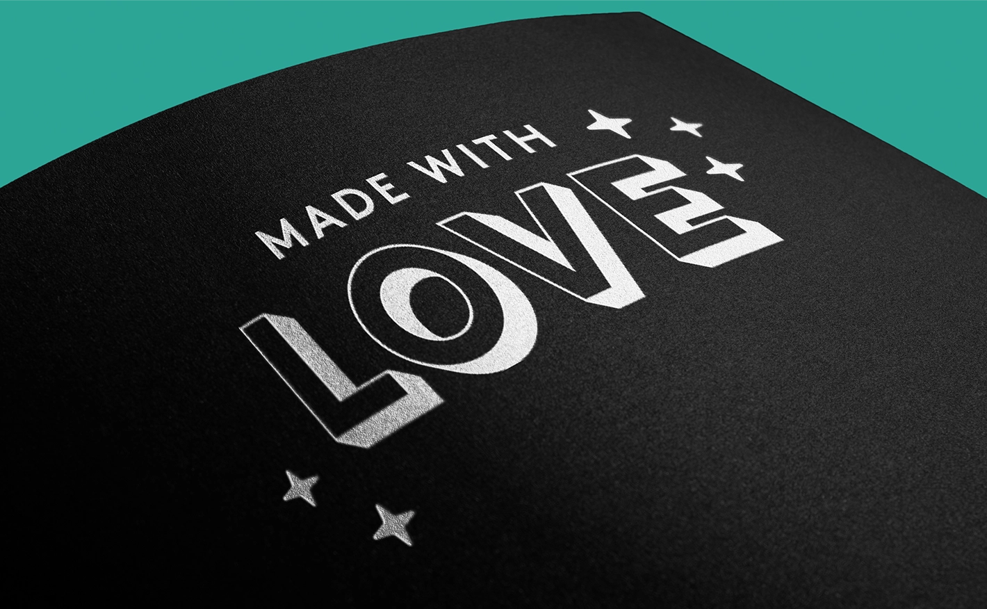 A close-up shot of heavy black textured paper printed with opaque white ink. The text reads "MADE WITH LOVE" in a bold, blocky 3D font style, accented by small white stars.