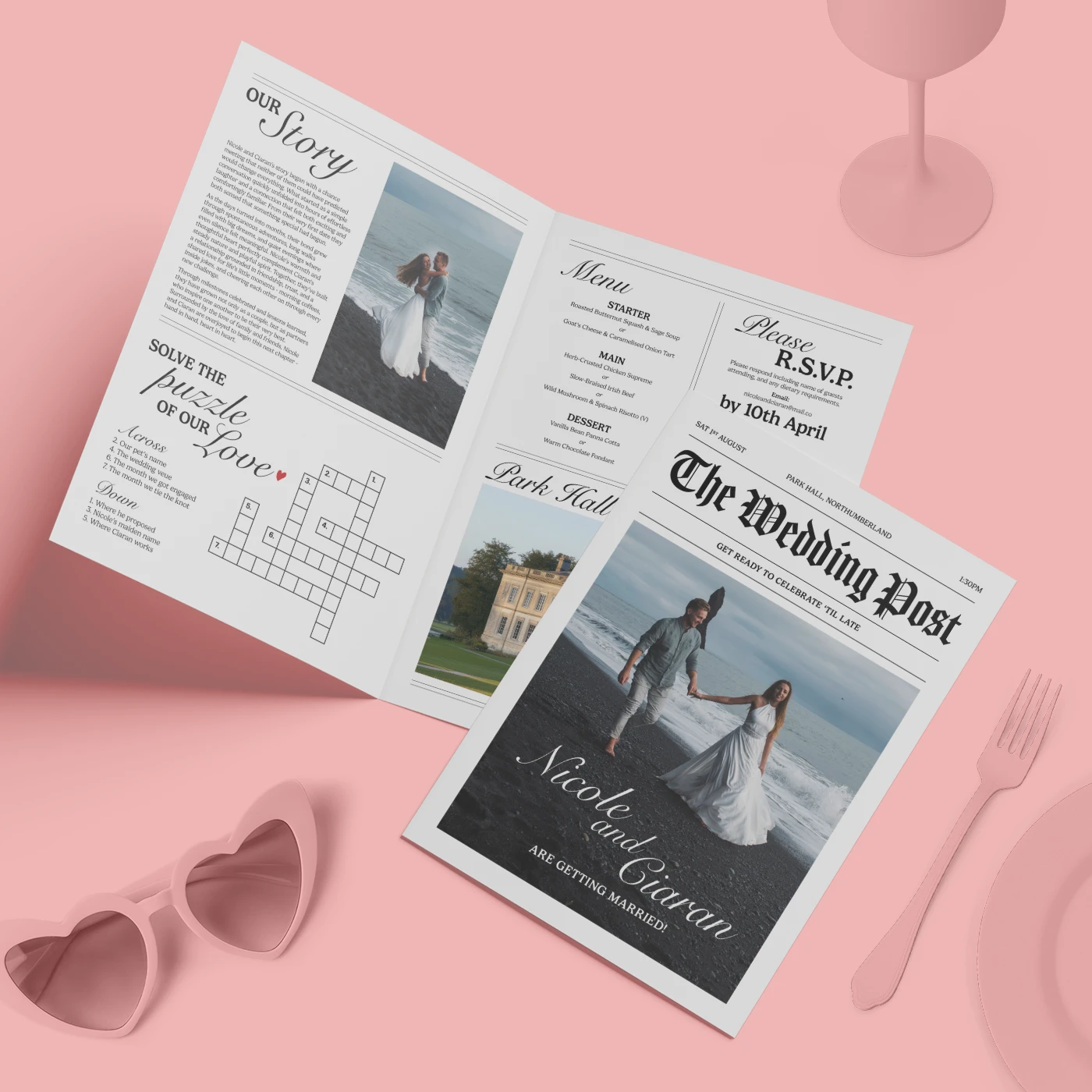 A custom wedding newspaper titled "The Wedding Post" for "Nicole and Ciaran" lies on a pink surface next to heart-shaped sunglasses, displaying a front-page photo of the couple on a beach and open pages featuring their love story, a crossword puzzle, a menu, and RSVP details.
