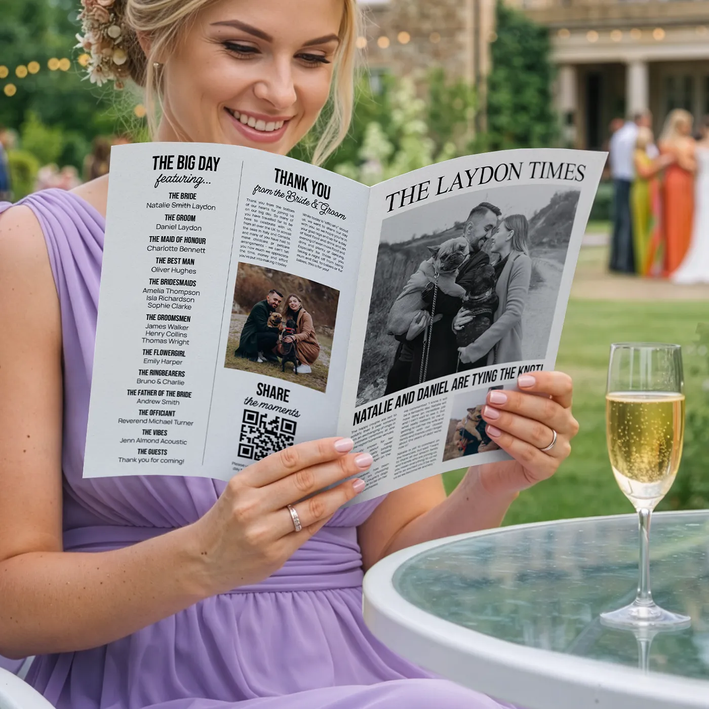 A smiling woman in a lavender dress sits at an outdoor table next to a glass of champagne, holding open a custom wedding newspaper titled "The Laydon Times" that features a black-and-white photo of a couple with their dog and sections titled "The Big Day" and "Thank You."